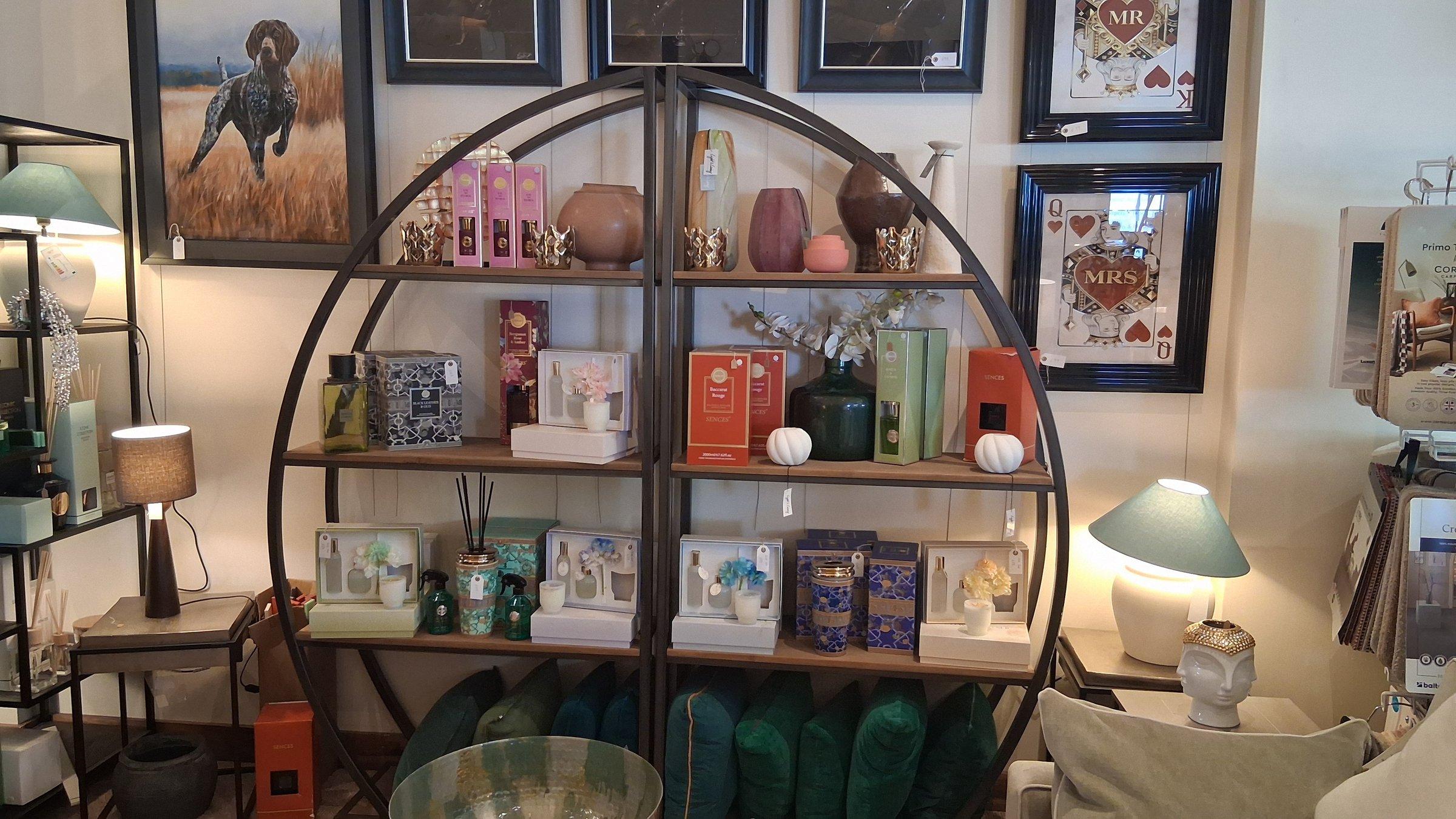 Circular metal shelving unit displaying home fragrance, vases and gift sets