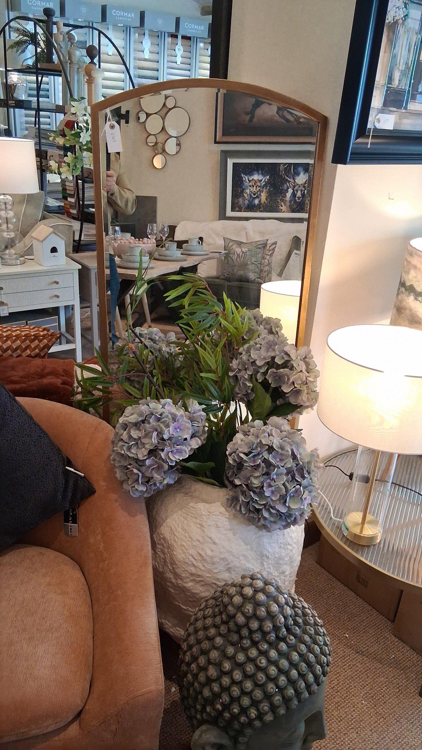 Arched mirror with stone vase of hydrangeas in the accessories area