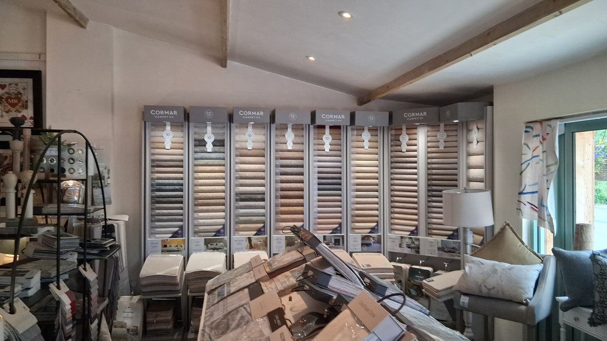 The carpet sample wall in the Canwell showroom, with rolled samples on the stands and fabric books on the table