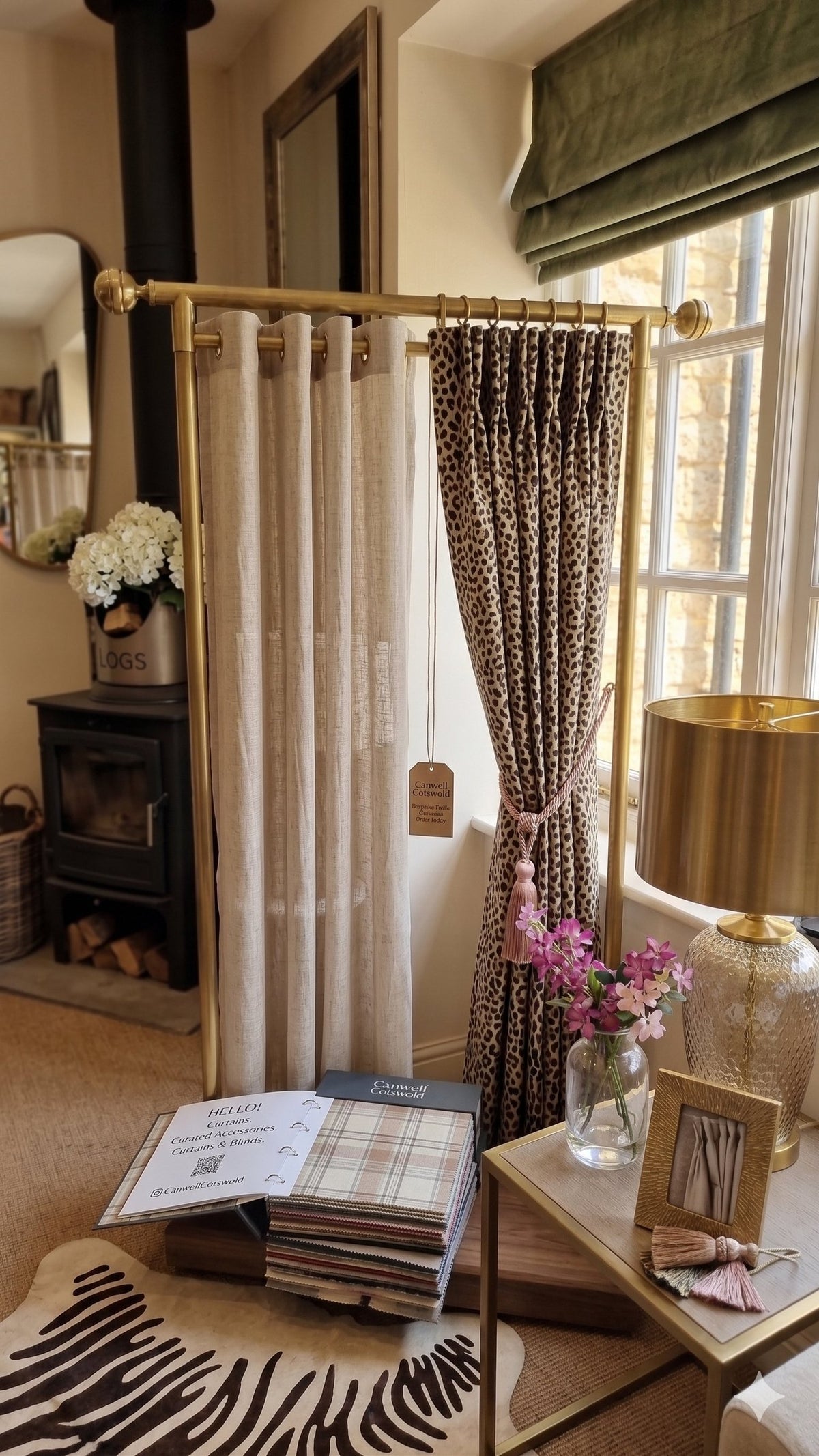 A curtain display stand in the Canwell showroom, with a linen curtain, a printed curtain with a tieback, and fabric books