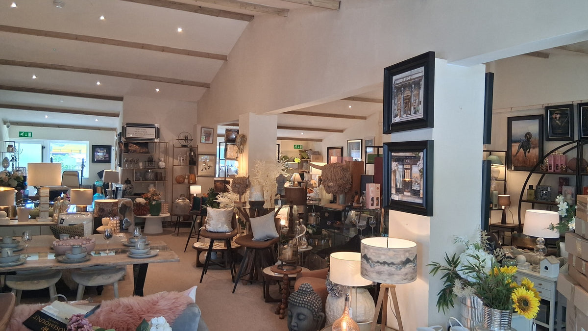 The accessories end of the Canwell showroom, with lamps, framed prints, cushions and a dining table set for two